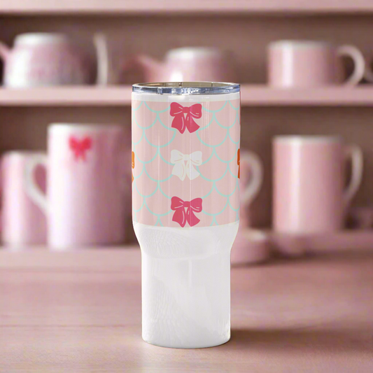 Light pink and multi-color mermaid travel mug with a handle.